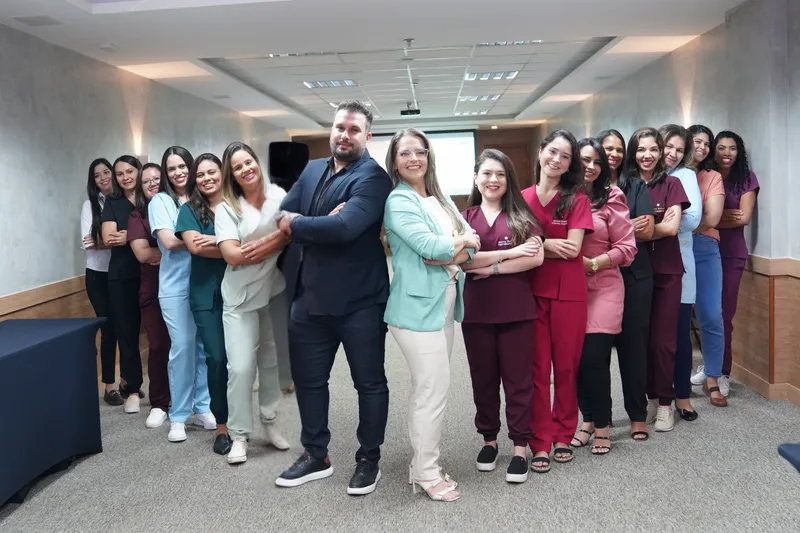 Equipe multidisciplinar da Baby Kids reunida e sorrindo na clínica, com terapeutas de braços cruzados em uniformes coloridos